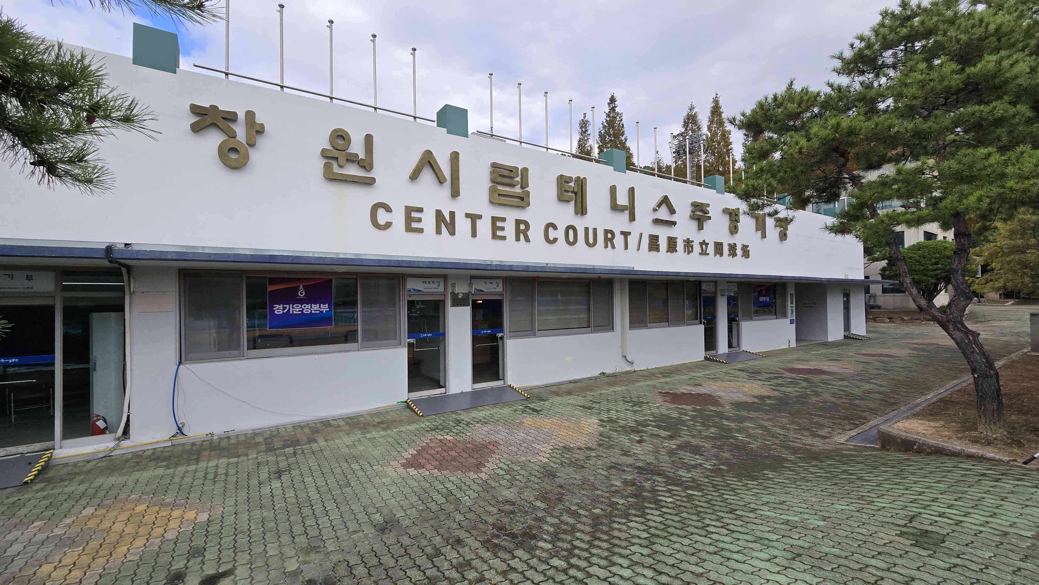 좌측 가장자리에서 바라본 창원시립테니스 주경기장 외관 전경이며, 좌측에 경기운영본부도 위치하고 있습니다.