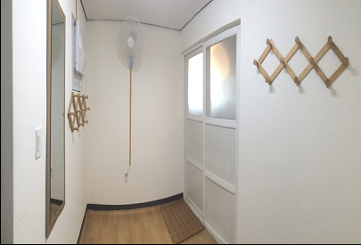 샤워실 앞에서 촬영한 내부 사진이며, 좌측부터 거울, 옷걸이, 선풍기가 비치되어있고 우측에 샤워실 문이 있습니다.