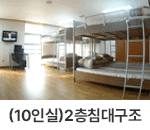 10인실(2층침대구조) : 창원축구센터 숙소동의 10인실 모습입니다. 오른쪽으로 2층 침대 3개가 위치하고 있습니다. 침대 옆으로는 큰 창이 있어 채광이 잘 들어오고, 창 옆에는 책상과 의자, 벽걸이 TV가 걸려있습니다. 밝은 하얀색 벽지와 우드 톤의 바닥이 따뜻한 느낌을 주는 공간입니다. 