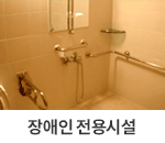 장애우 전용시설 : 창원축구센터의 장애우 전용 시설 내부 모습입니다. 샤워 공간은 장애인을 위한 안전한 설계로 구성되어 있습니다. 벽면에는 손잡이가 설치되어 있어 이동 중 지지대로 활용할 수 있습니다. 샤워 헤드와 수전은 사용하기 편리한 높이에 배치되어 있으며, 벽면에는 작은 선반이 있어 샤워 용품을 보관할 수 있습니다. 전체 공간은 따뜻한 톤의 타일로 마감되어 있으며, 실용성과 안전성을 모두 고려한 구조로 설계되었습니다.