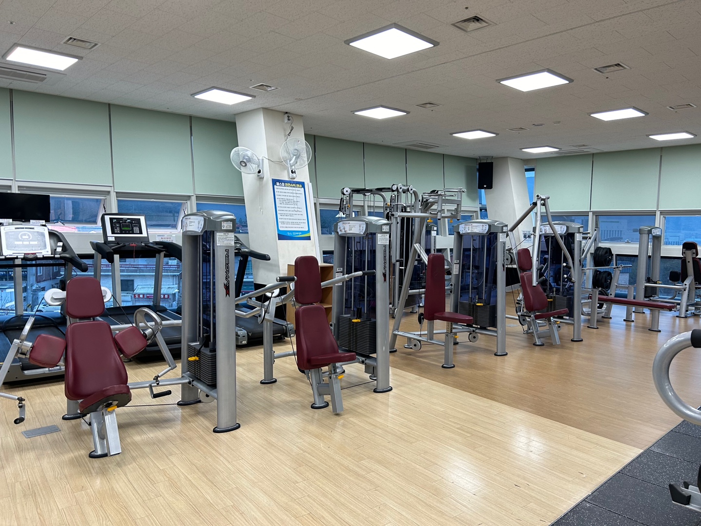 성산스포츠센터 2층에 위치한 헬스장 내부이며, 유산소 운동을 위한 실내자전거 및 런닝머신이 나열되어 있는 사진입니다.