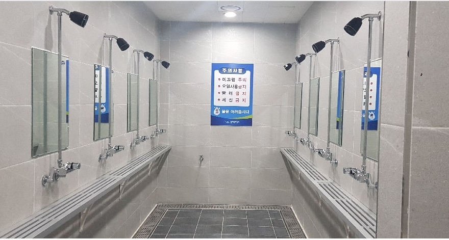 샤워실 내부 사진이며, 샤워기, 거울, 선반이 비치되어 있고 안쪽 벽면에는 주의사항이 안내되어 있습니다.(미끄럼 주의, 오일사용금지, 빨래 금지, 세신 금지)