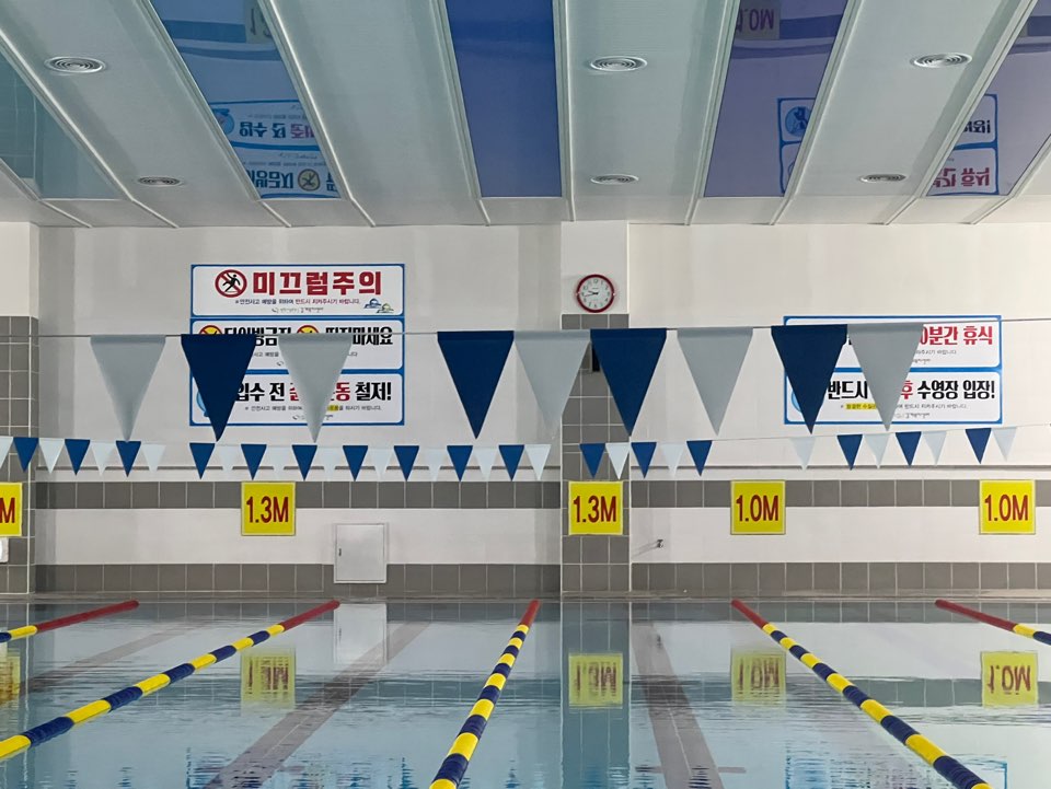 정면에서 안쪽벽면으로 바라본 의창스포츠센터 내 수영장 내부 사진이며, 벽면에 안내문구와 각 레인별 수심 정도를 나타내고 있습니다.