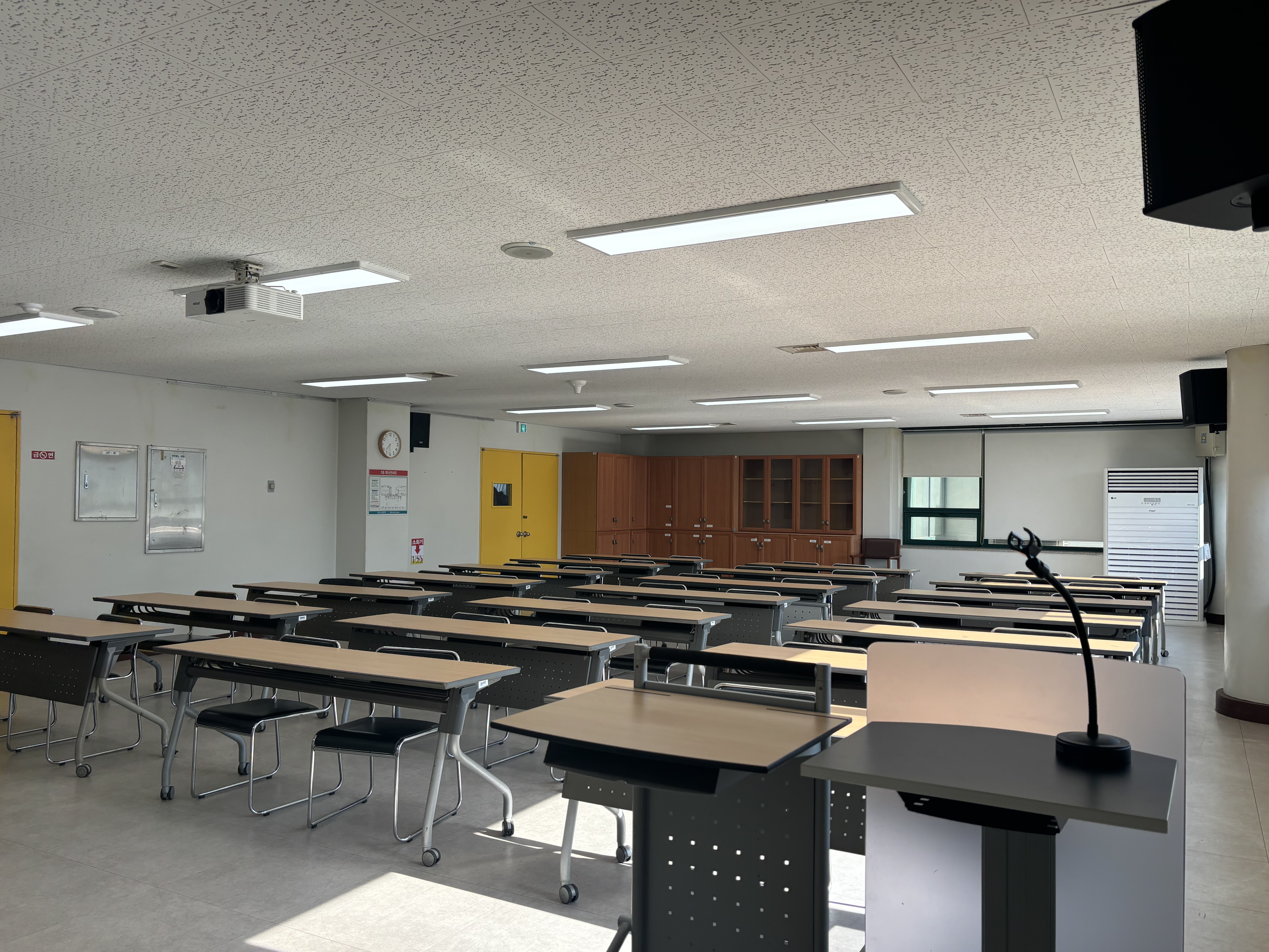 늘푸른전당의 교육실2 내부 앞 쪽에서 촬영한 사진이며, 2인 책상 및 좌석이 일렬로 나열 및 3분단으로 분리되어 있습니다.