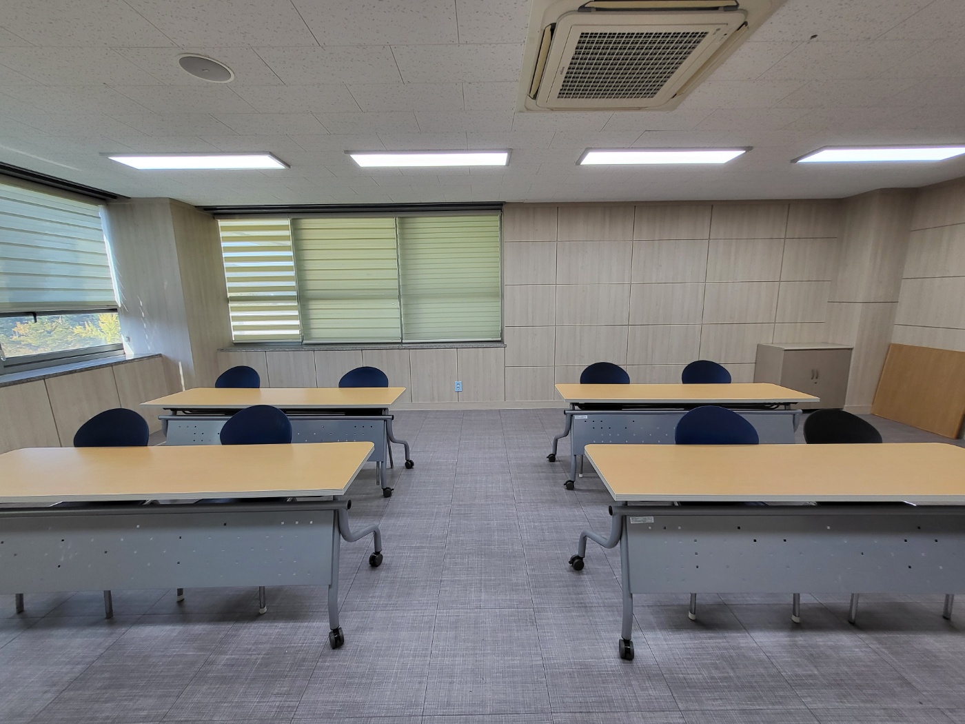 늘푸른전당의 프로그램실1 화이트보드 앞 쪽에서 촬영한 사진이며, 내부에는 2인 책상 2분단으로 2개씩 나열되어 있습니다.