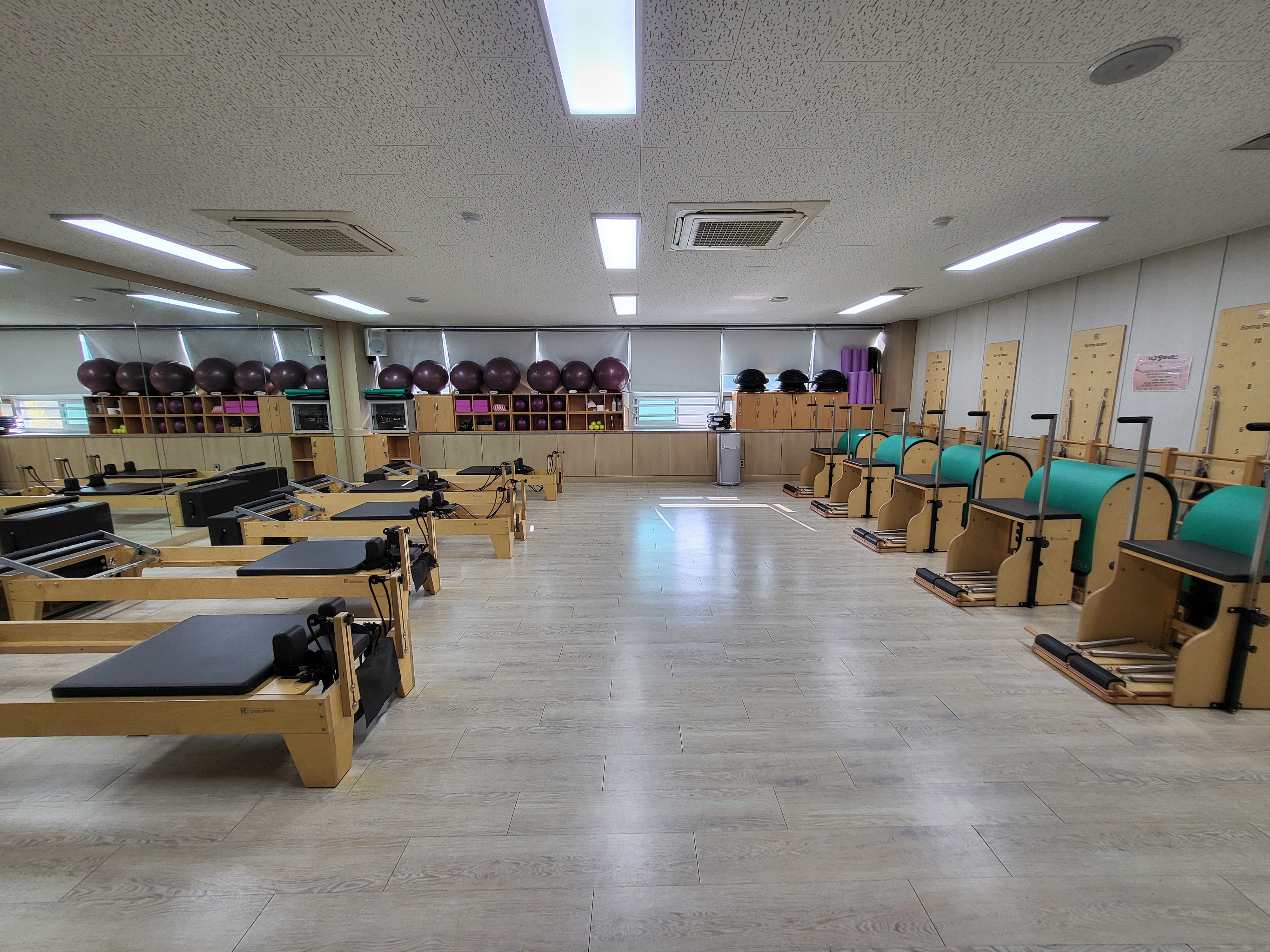 늘푸른전당의 프로그램실2 내부를 촬영한 사진이며, 안쪽 선반 위에는 프로그램을 위한 짐볼 등 도구가, 실 양쪽에는 기구(리포머, 체어)가 나열되어 있습니다.