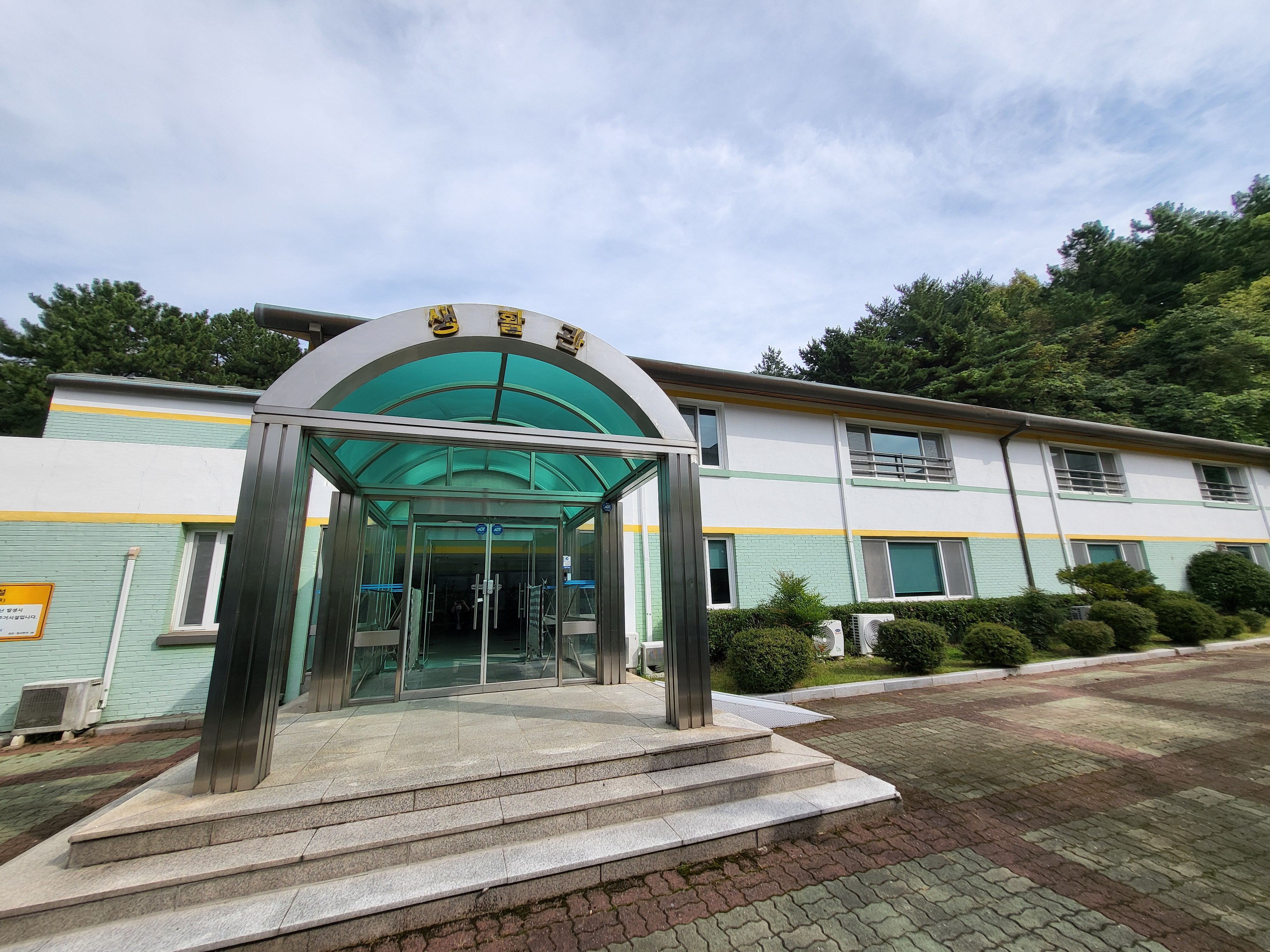 지상에서 바라본 생활관 외관 및 전경이며, 계단 및 우측 경사로를 통해 입구로 들어가실 수 있습니다.