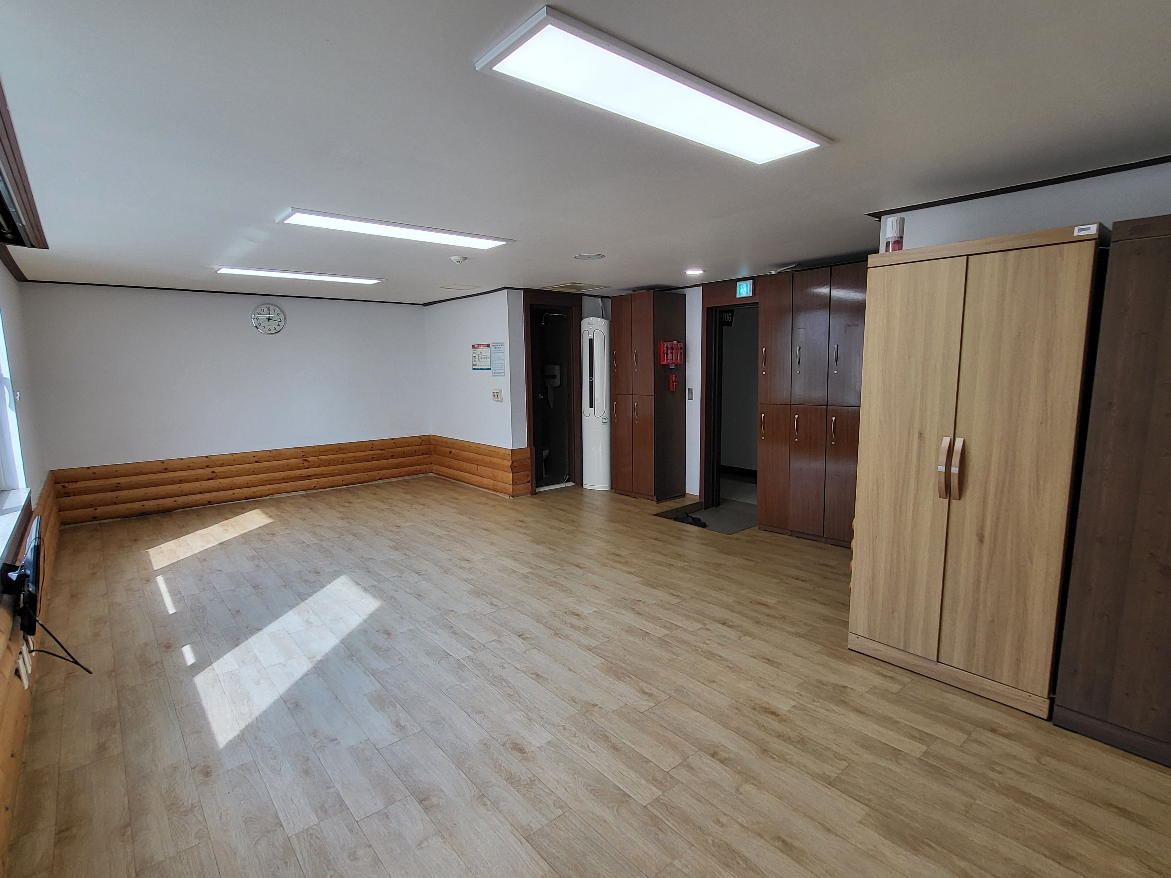 생활관 안쪽 가장자리에서 전체 내부를 촬영한 사진입니다. 입구 맞은편에는 창문이 있고 좌측에는 옷장과 사물함이, 입구 우측에는 화장실이 있는 구조입니다. 중앙에는 비어있습니다.