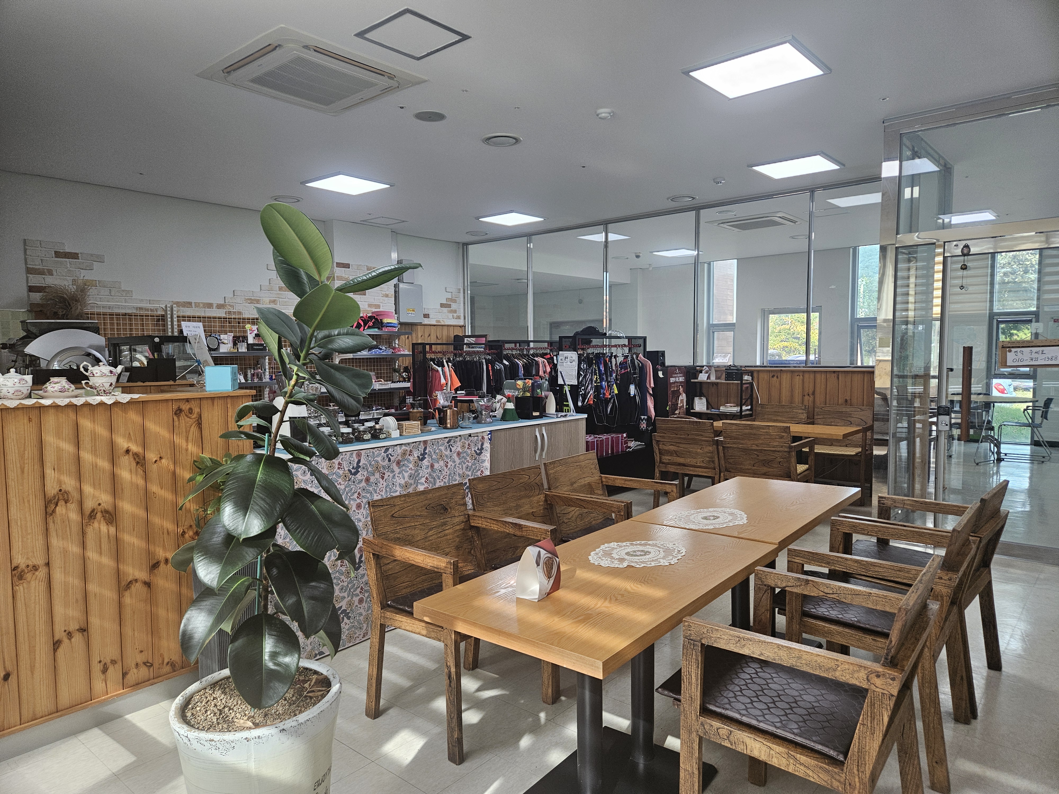 진동종합복지관 북카페 건물 사랑방 편의점 실내 모습이며 앞쪽에는 음료를 마실 수 있는 책상과 의자가 비치되어있고, 좌측에는 음료를 제조하는 공간이 위치해 있다.
