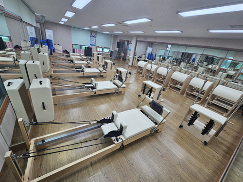 진해국민체육센터의 1층 기구필라테스실 전체 내부 사진이며, 양쪽 벽면 거울 앞 프로그램 운영을 위한 기구가 배치되어 있습니다.