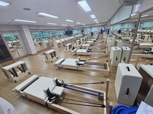 진해국민체육센터의 1층 기구 필라테스실 안쪽 가장자리에서 바라본 전체 사진이며, 일렬로 기구들이 배치되어 있습니다.