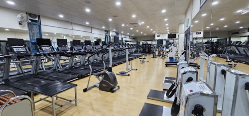 진해국민체육센터의 헬스장 내부에서 정면으로 바라본 운동기구를 촬영한 사진이며 유산소 기구(웨이트 등)들이 배치되어 있습니다.