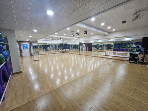 진해국민체육센터의 3층 다목적실 내부이며 우측 안쪽 가장자리에서 촬영한 사진이며, 입구를 기준으로 우측에는 프로그램 운영을 위한 짐볼 등 필라테스 도구가 비치되어 있고 좌측에는 남자 탈의실이 위치해 있습니다.