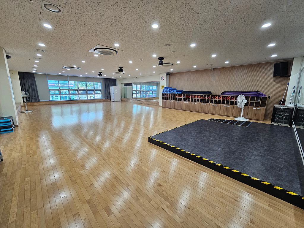 입구에서 바라본 휘트니스실 내부이며, 높은 층고와 넓은 공간을 제공하고 있으며 거울 벽, 프로그램을 위한 도구 등이 비치되어 있습니다.