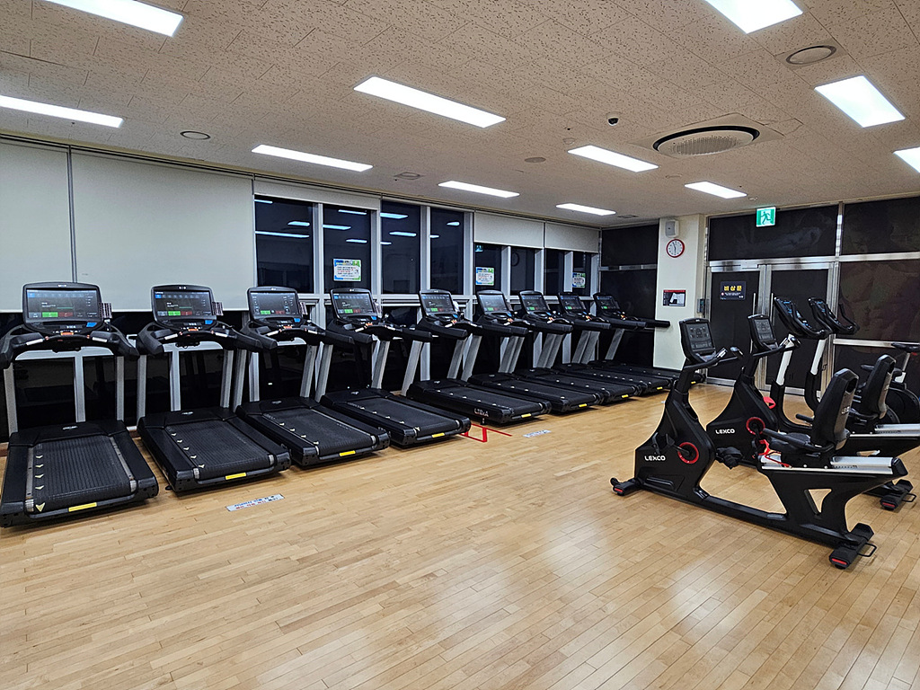 내부에서 바라본 헬스장 유산소실이며, 창가 쪽으로 머신러닝이 일렬로 나열되어 있으며 우측에는 사이클이 위치해 있습니다.