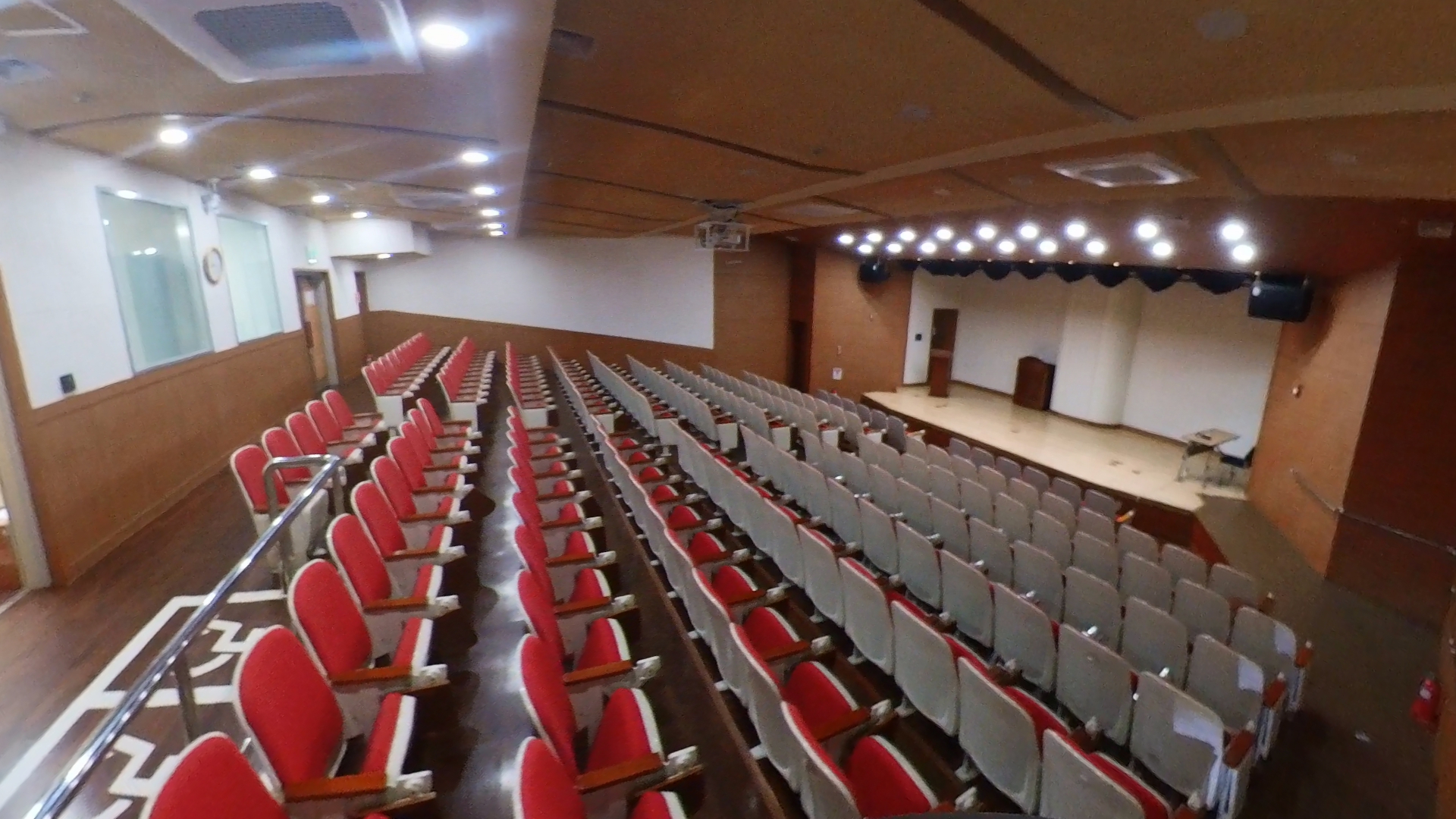 우리누리청소년문화센터의 소공연장 내부 객석 뒤쪽 측면에서 바라본 사진이며, 앞쪽무대 위 조명이 비춰지고 있으며, 객석이 일렬로 나열되어 있습니다.
